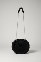 Black crochet handbag with chain strap on a floral fabric background