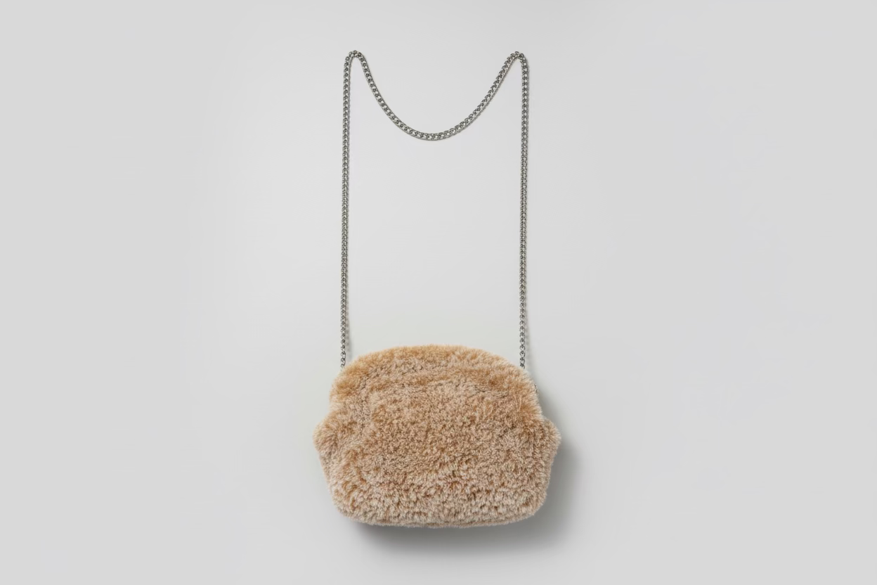 Brown fur handbag with a chain strap on a floral-patterned fabric background